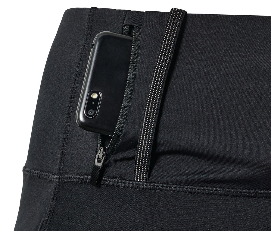 Detail čiernych bežeckých legínsov s vreckom na zips, v ktorom je zasunutý mobilný telefón.