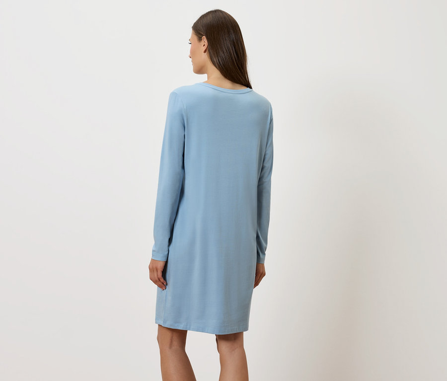 Žena chrbtom k fotoaparátu má na sebe modré šaty s dlhým rukávom.