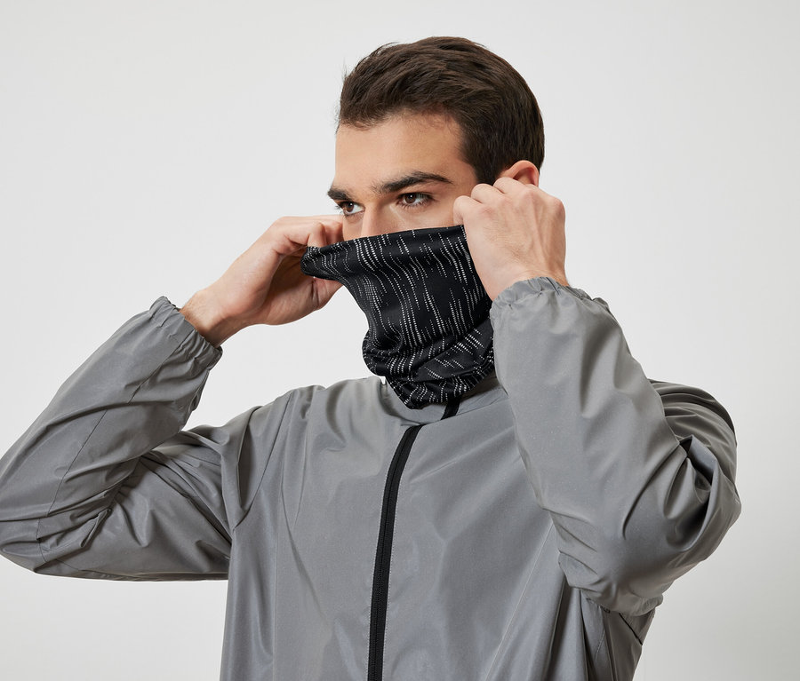 Muž si oblieka čierny nákrčník s bielymi prúžkami a má na sebe sivú bundu.