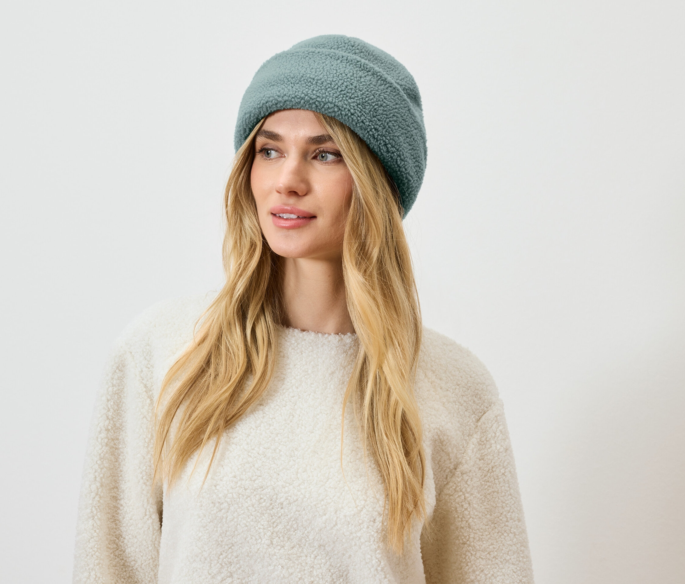 Žena s blond vlasmi a modrozelenou čiapkou.