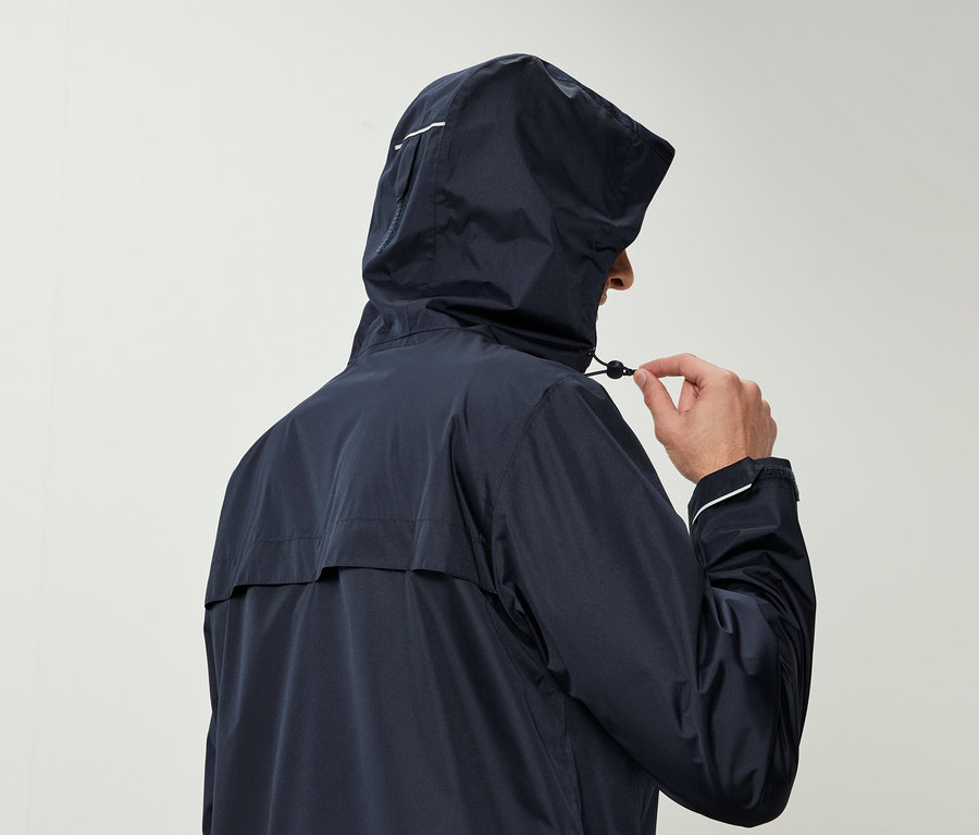 Muž v tmavomodrej bunde s kapucňou sťahuje šnúrku na kapucni.