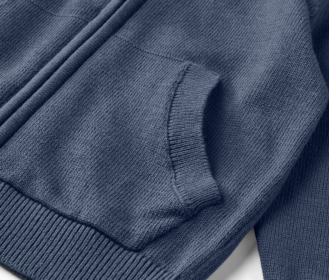 Detail modrého detského pleteného svetra so zipsom a vreckom.