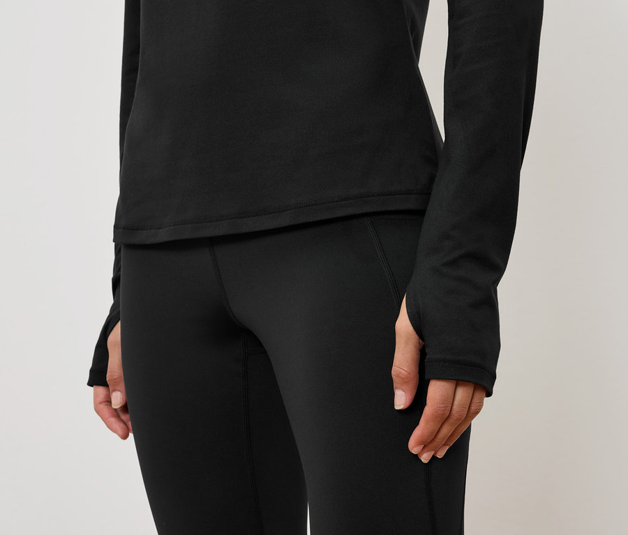 Detail dámskeho čierneho športového outfitu s dlhým rukávom a legínami.