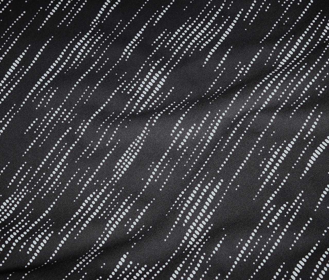 Detailný záber na čiernu látku s diagonálnymi, bodkovanými, bielymi líniami.