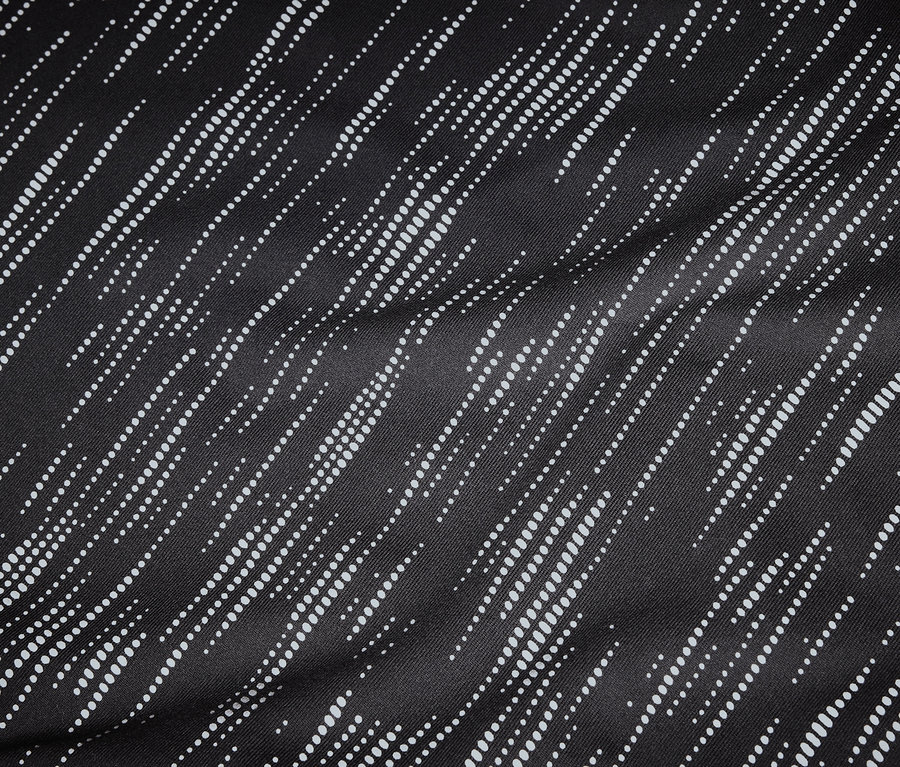 Detailný záber na čiernu látku s diagonálnymi, bodkovanými, bielymi líniami.