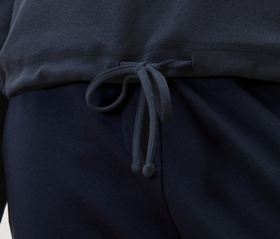 Detailný záber tmavomodrého topu so sťahovacou šnúrkou nad tmavomodrými nohavicami.