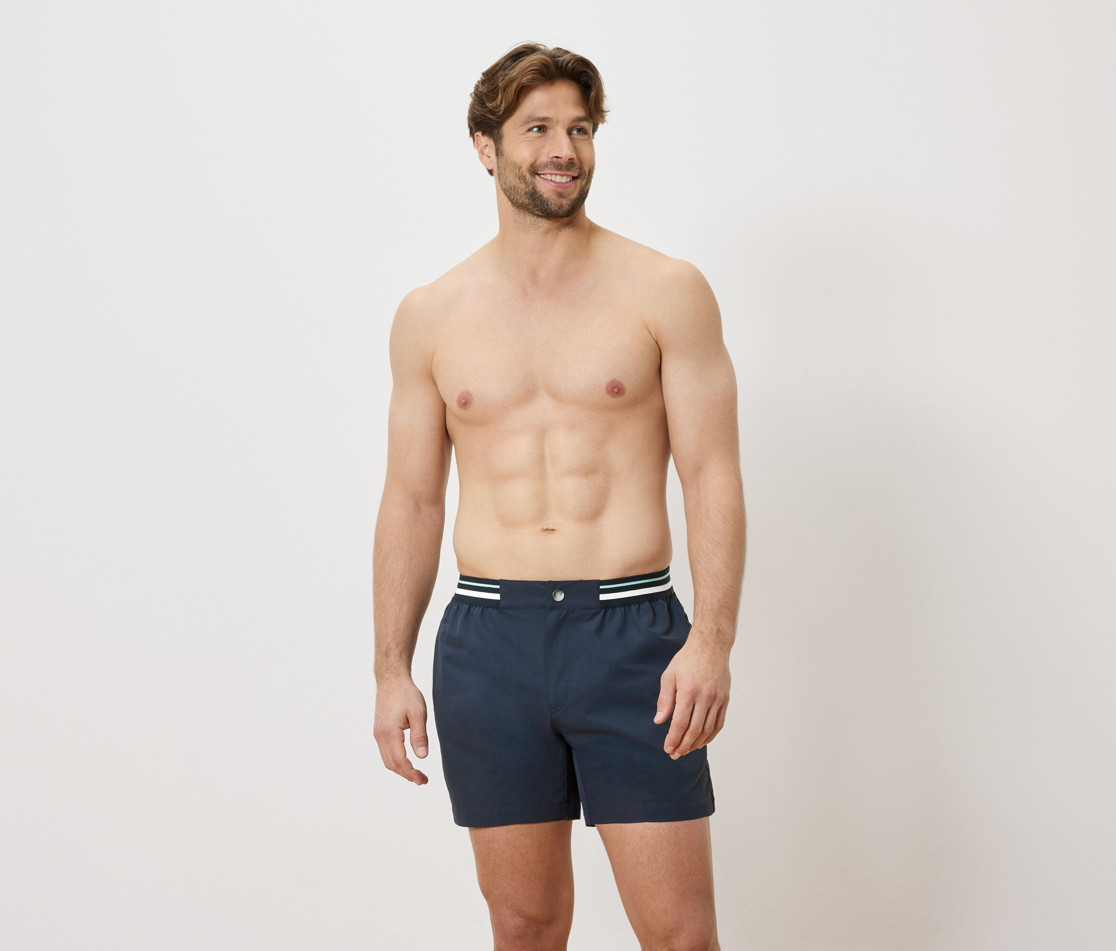 Muž s odhaleným vrchom tela má na sebe modré boxerky s bielym a zeleným pásom na bielom pozadí.