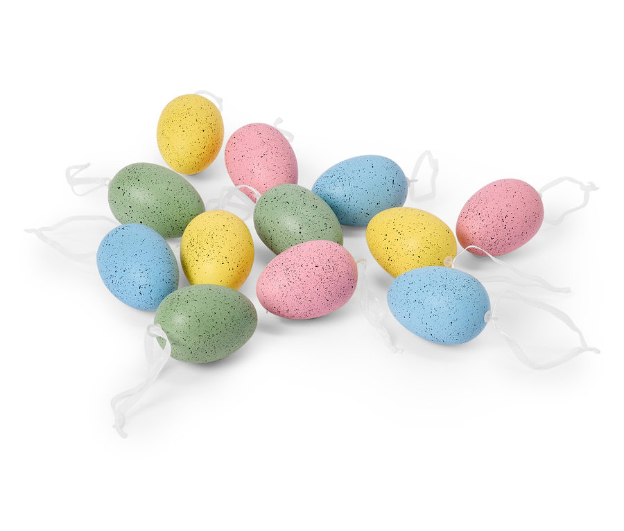 Na bielom pozadí leží tucet pastelových veľkonočných vajíčok s bielymi stužkami.