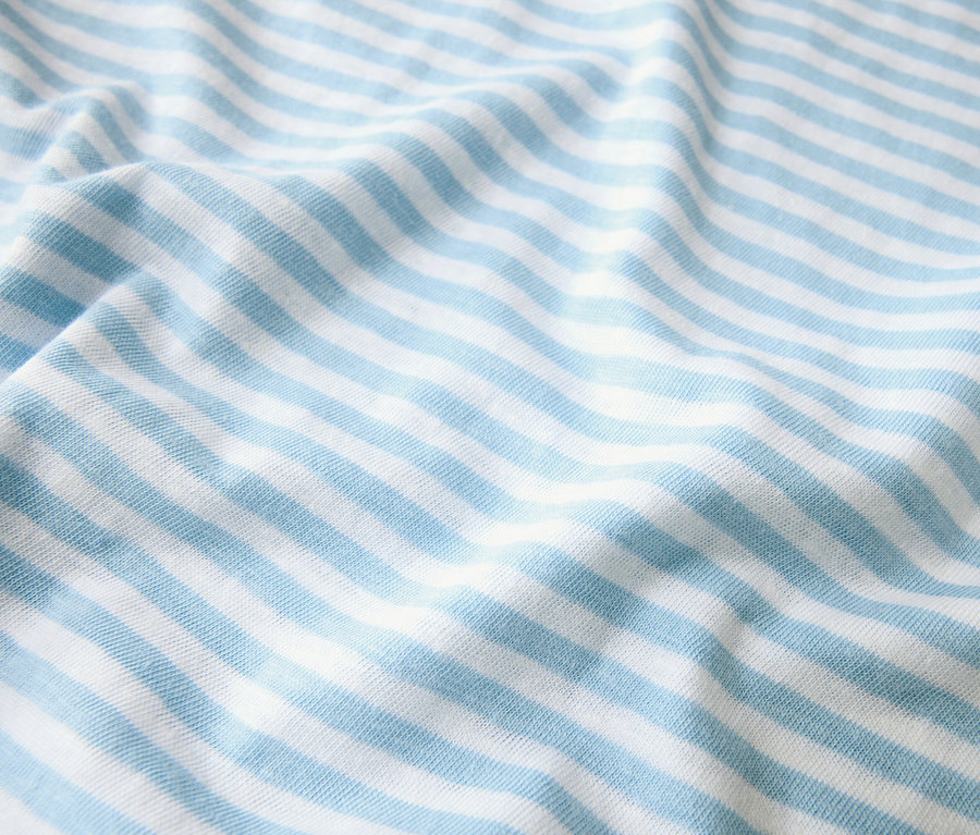 Detail záberu látky so svetlomodrými a bielymi pruhmi, ktorá je poskladaná.