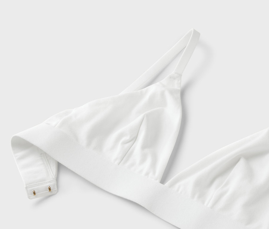 Detailný záber bielej podprsenky s tenkými ramienkami na bielom pozadí.