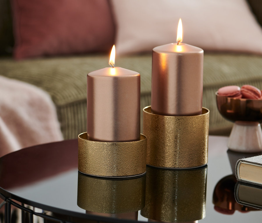 Dve horiace ružovozlaté sviečky stoja na zlatých svietnikoch na lesklom stolíku. 2 svietniky.
