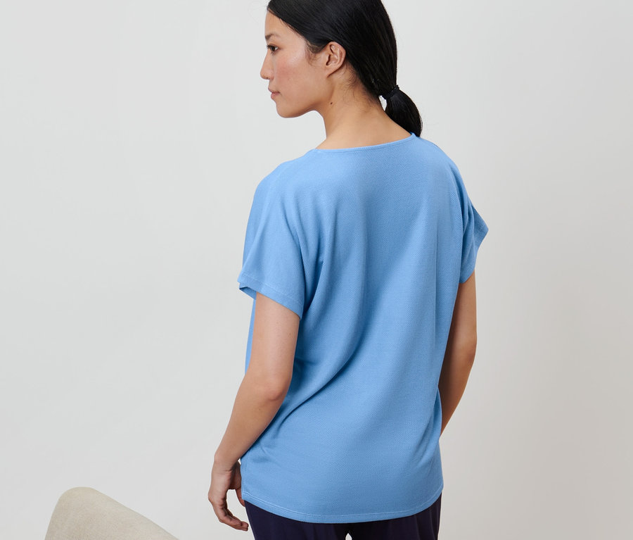 Žena má na sebe svetlomodré štruktúrované tričko.