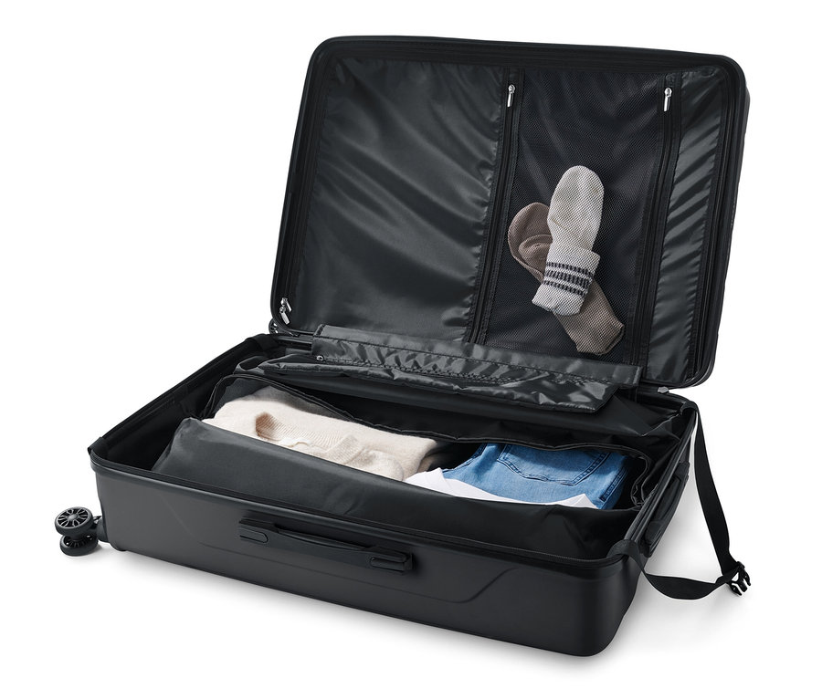 Otvorený veľký kufor s tvrdou škrupinou s oblečením vnútri.