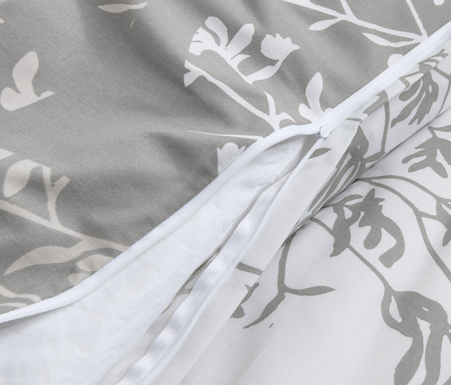 Detail sivej posteľnej bielizne renforcé s kvetinovým vzorom a zipsom.