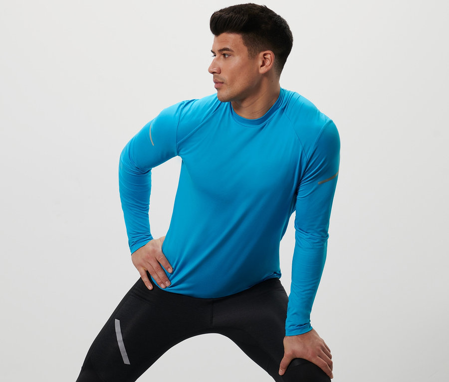 Muž robí strečing v neónovomodrom funkčnom tričku s dlhými rukávmi.