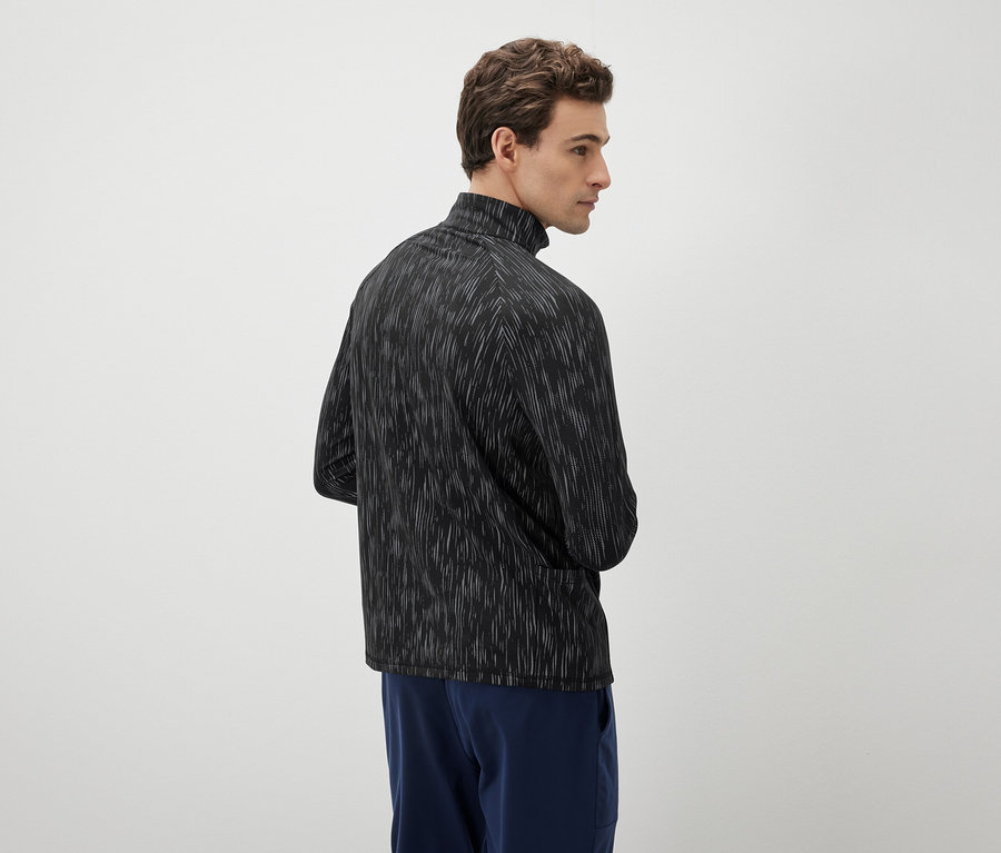 Muž sa pozerá doľava a má na sebe čierno-biely top a modré nohavice.