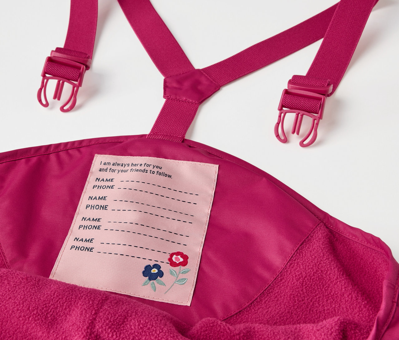 Detail detských termo nohavíc do dažďa vínovej farby s podbradníkom a štítkom na meno.