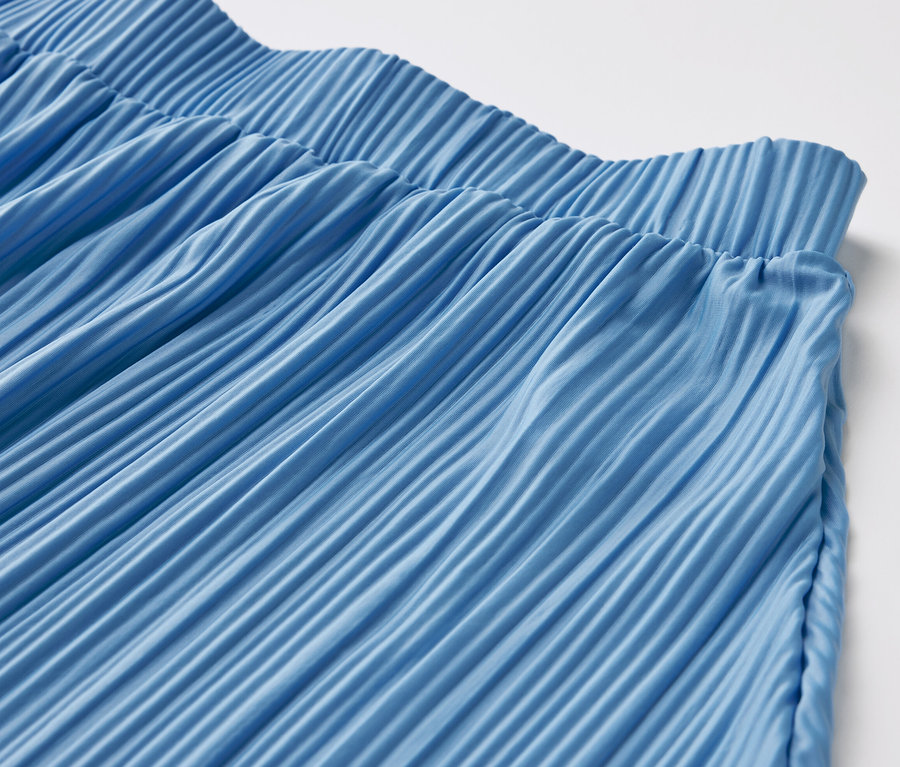 Detail modrej plisovanej sukne.