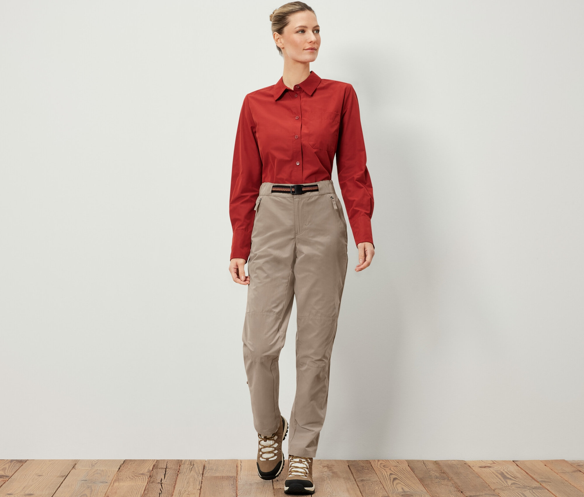 Žena má na sebe outdoorové nohavice s ochranou proti komárom, hnedú košeľu a turistické topánky.