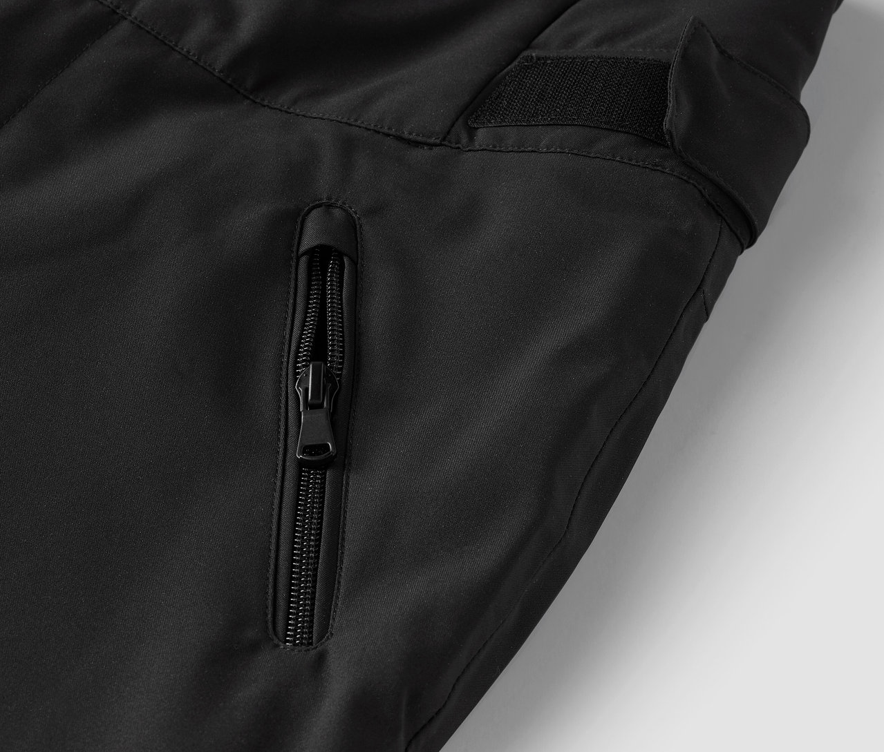 Detail čiernych nohavíc s vreckom na zips.