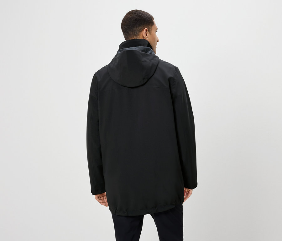 Muž chrbtom k fotoaparátu má na sebe čiernu bundu s kapucňou a čierne nohavice.