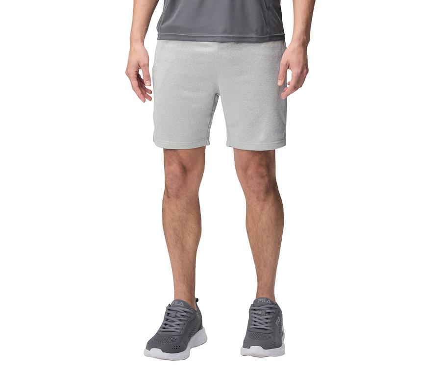 Muž má na sebe sivé šortky a sivé tenisky Fila.