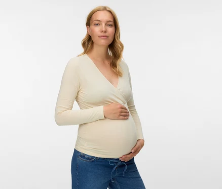 Tehotná žena v béžovom tope MAMALICIOUS »MLKERRIE« z 2-balenia a džínsoch, držiaca si brucho.