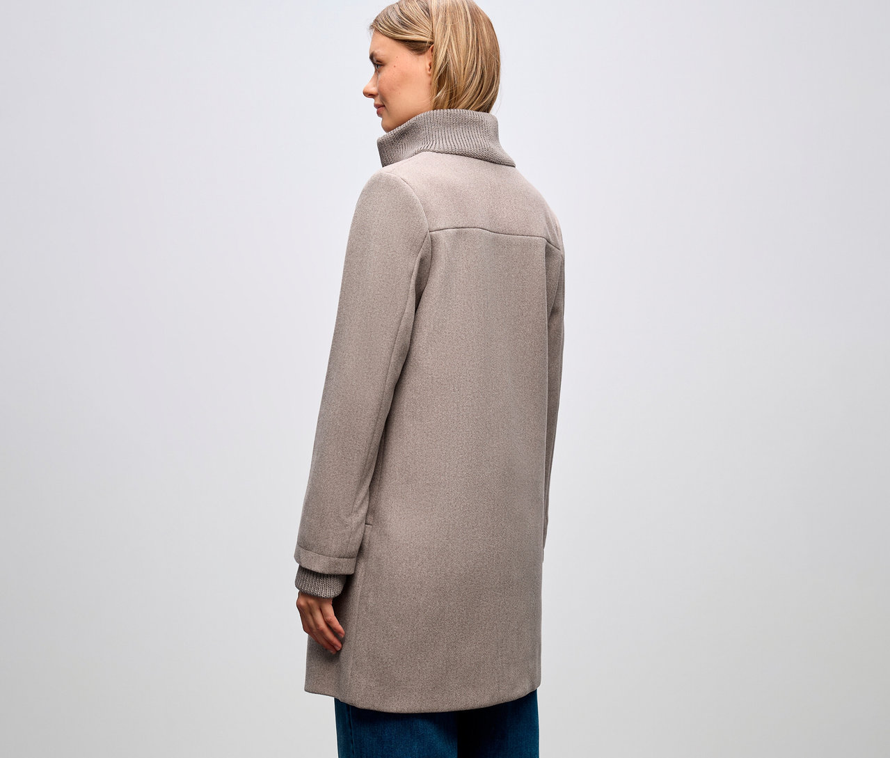 Žena z profilu, má na sebe krátky kabát Street One a modré džínsy.