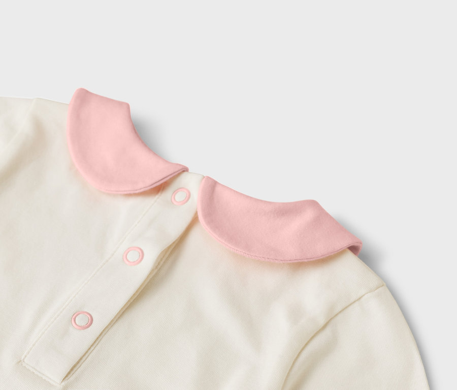 Detailný pohľad na krémový top s ružovým golierom a gombíkmi.