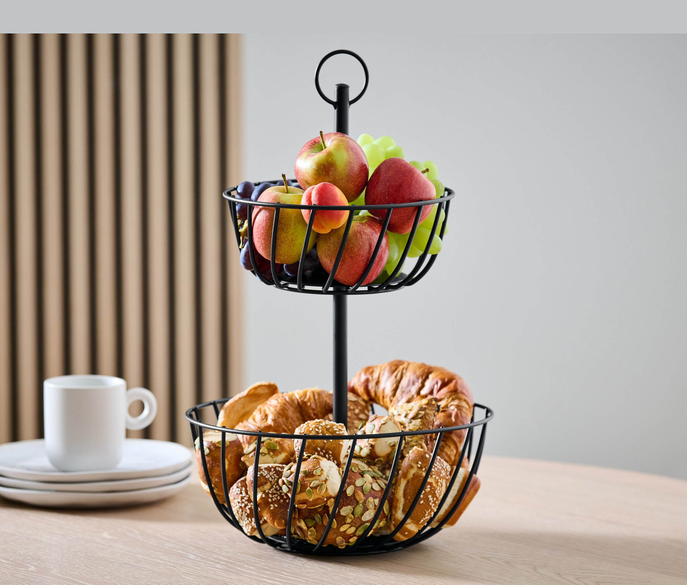 Dvojposchodový etažér s ovocím a pečivom na stole.