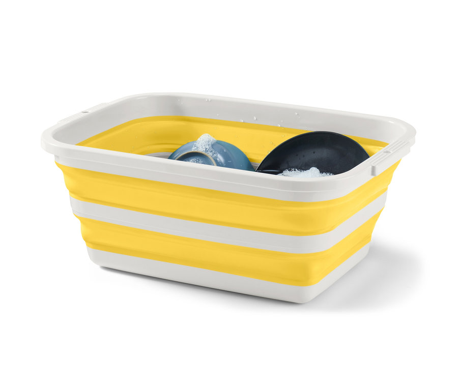 Skladací kôš na bielizeň žltej a bielej farby s umývacími prostriedkami a riadom vnútri.