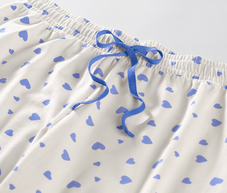 Detail pyžamových nohavíc so srdiečkami a modrou sťahovacou šnúrkou.