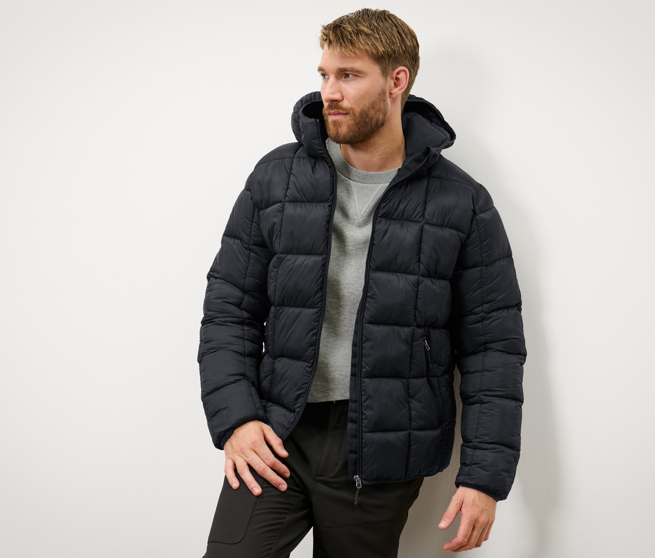 Muž má na sebe čiernu prešívanú bundu.