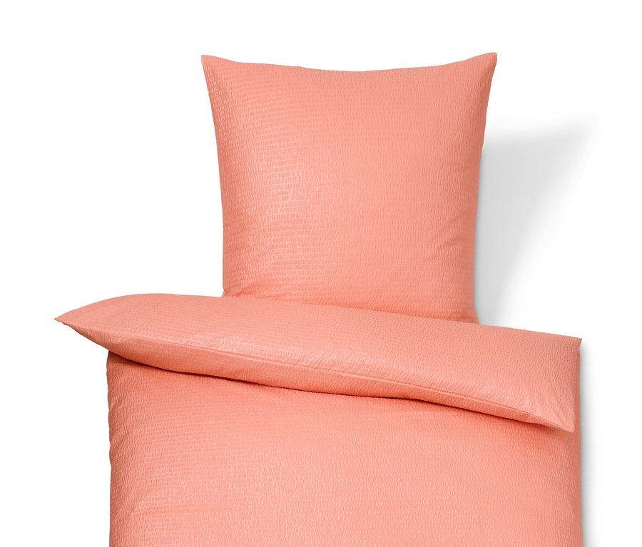 Korálové krepové obliečky štandardnej a nadmernej veľkosti ležia na bielom pozadí.