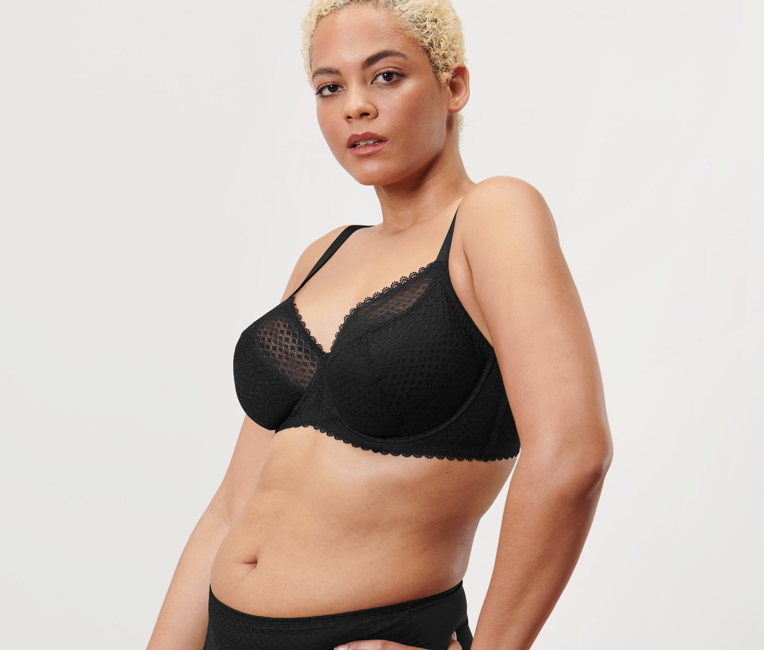 Žena pózuje v čiernej podprsenke s kosticami.