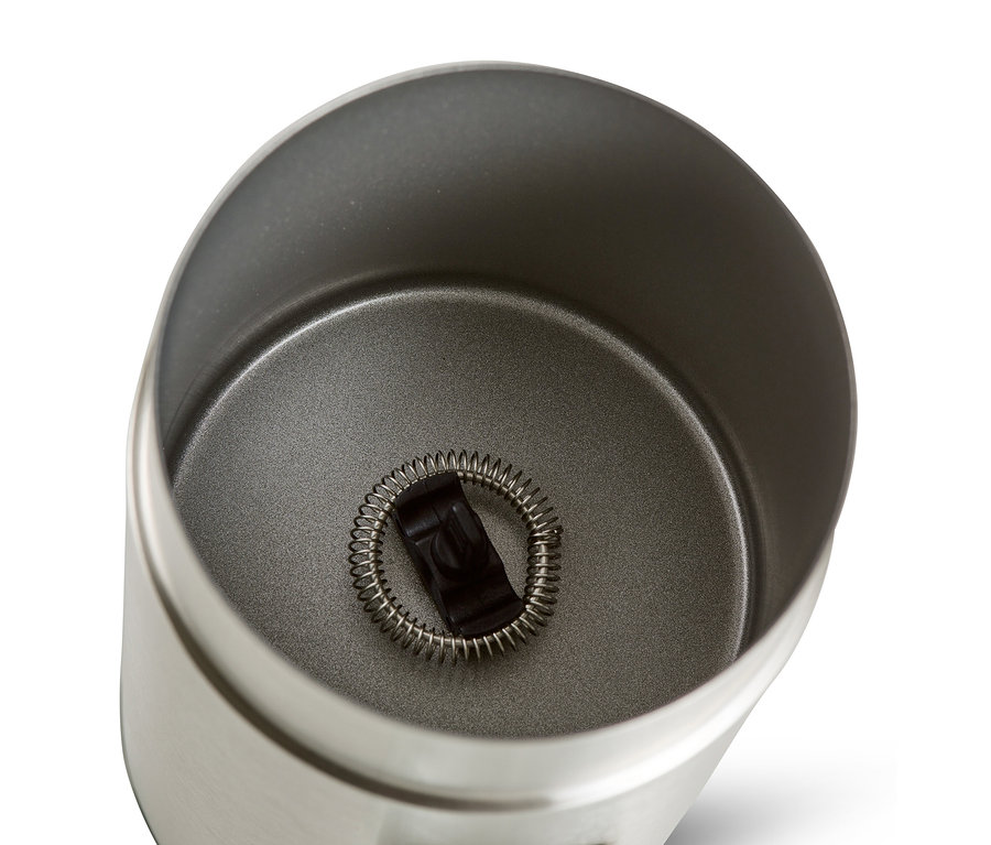 Pohľad zhora do elektrického napeňovača mlieka z ušľachtilej ocele s metličkou vnútri.