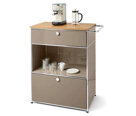 Kávovar a french press na hnedej komode so zásuvkami, pohármi a šálkami.