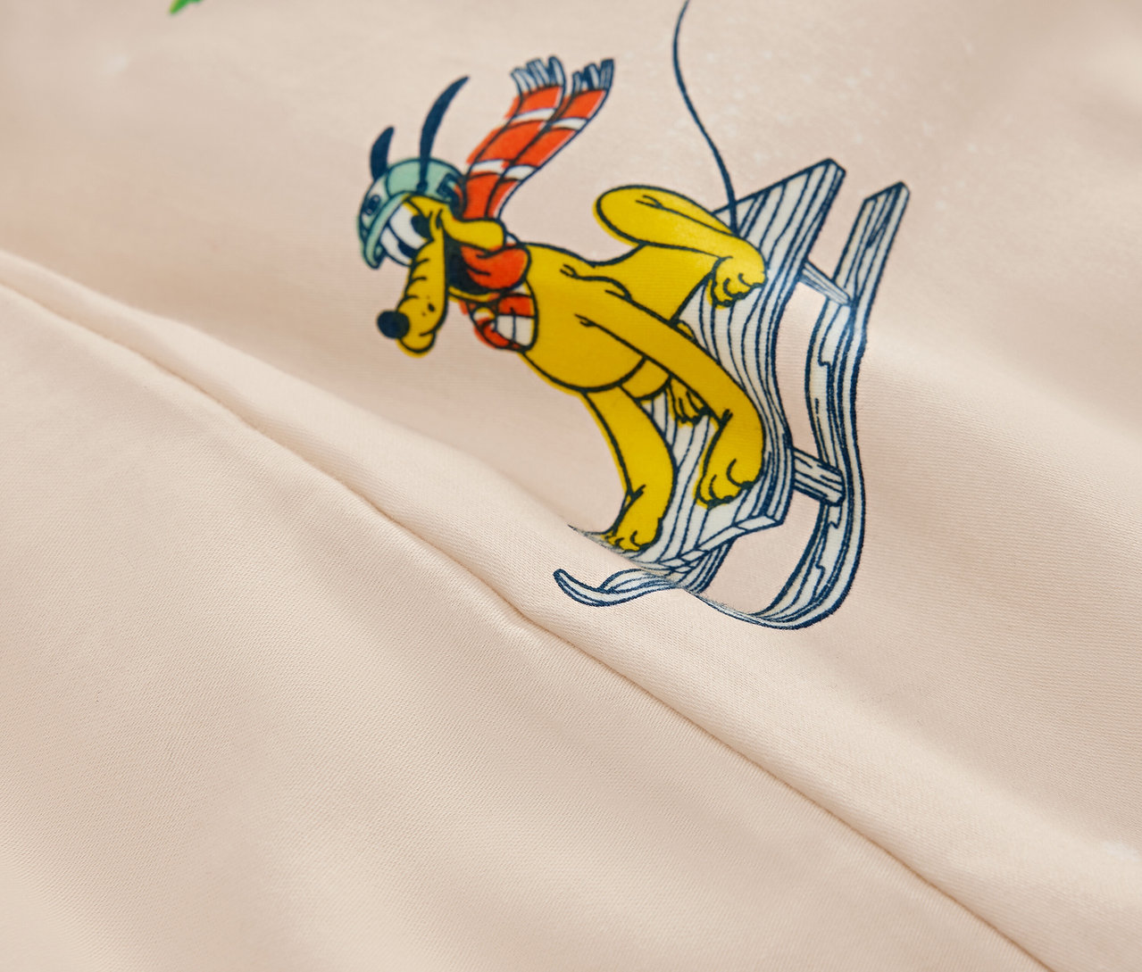 Kreslený obrázok žltého psa s helmou a šálom na lyžiach na béžovom pozadí.