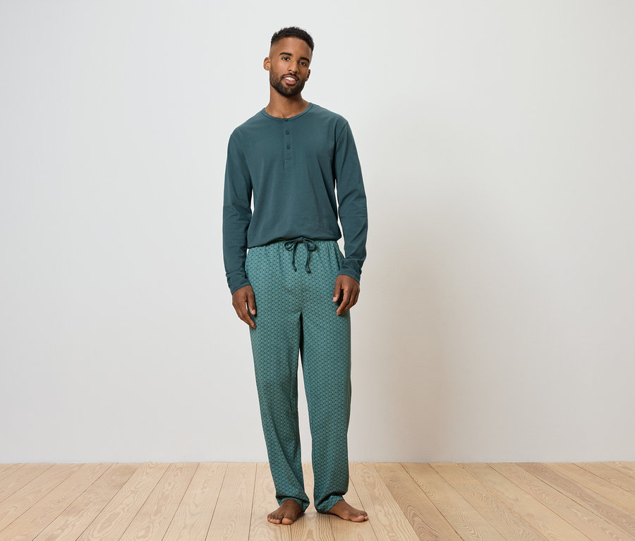 Muž stojí a má na sebe zelené pyžamo.