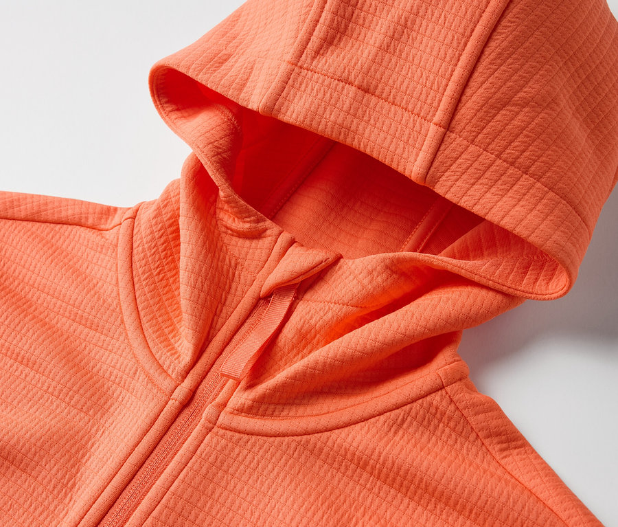 Detail oranžovej funkčnej bundy s kapucňou.