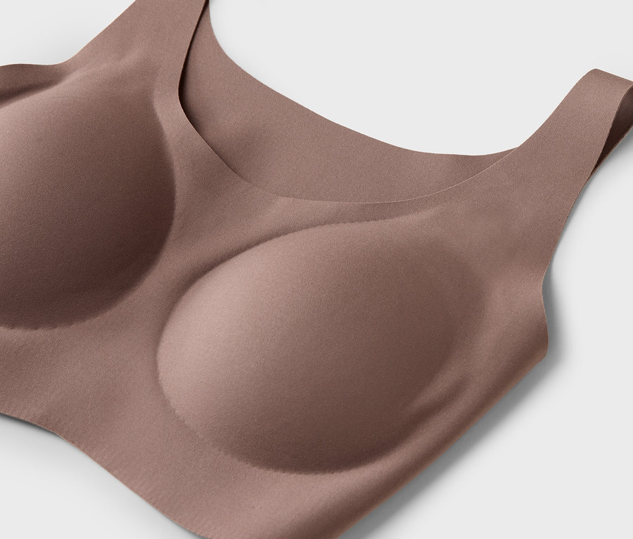 Detailný záber telovej podprsenky s tvarovanými košíčkami na bielom pozadí.