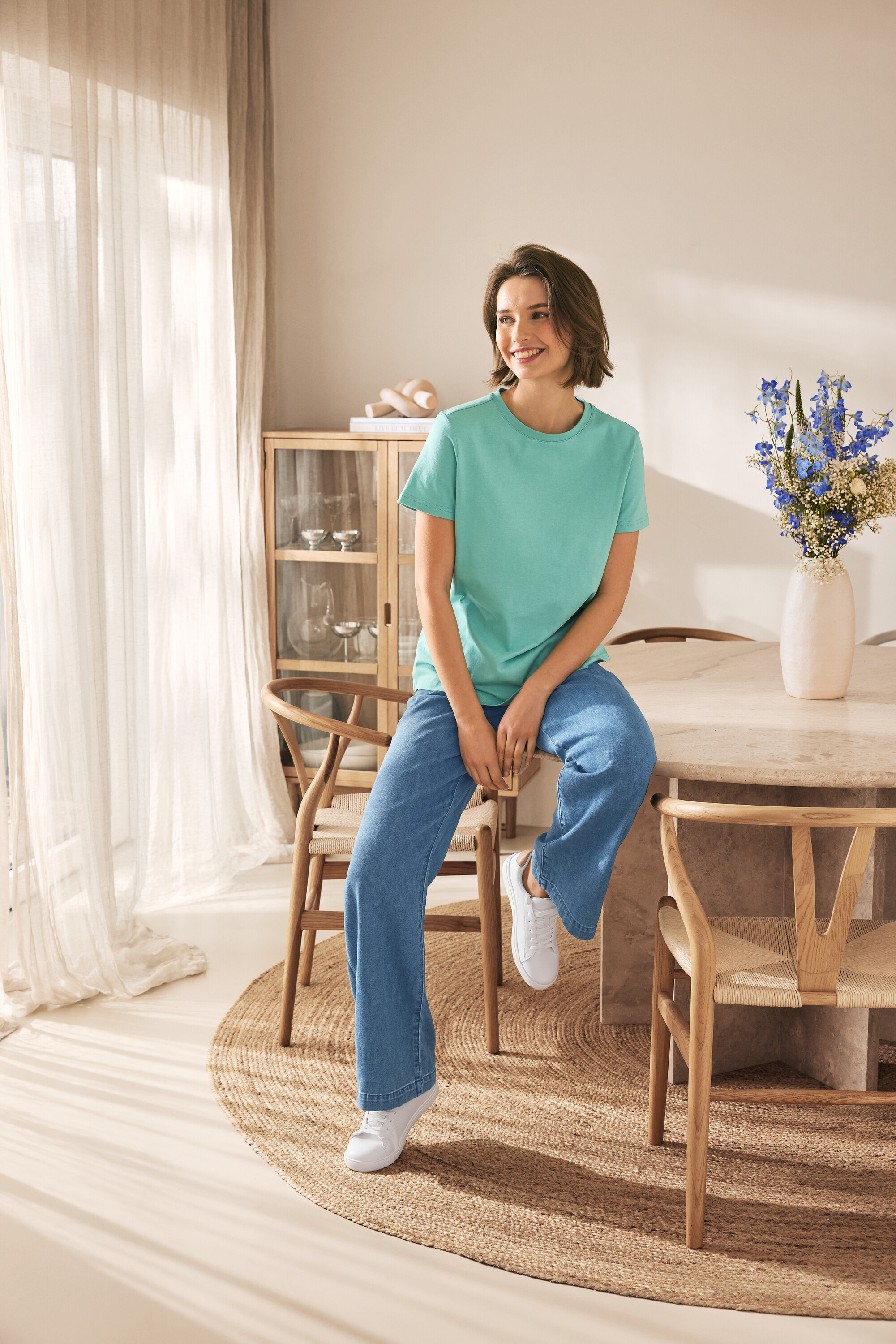 Žena sedí na stoličke a má na sebe kožené tenisky.