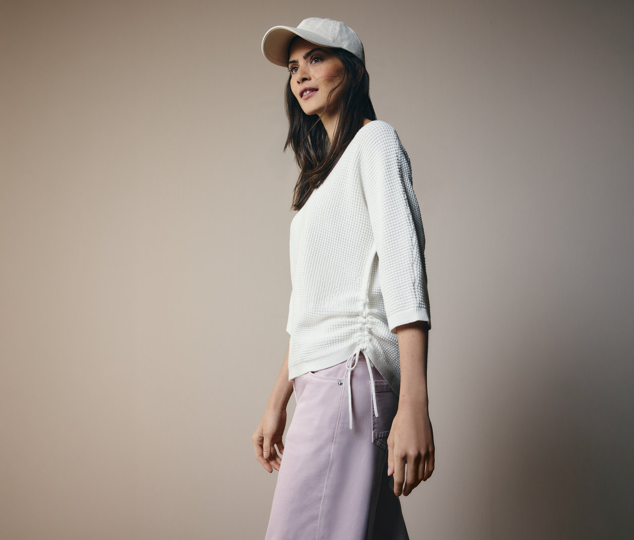 Žena s šiltovkou a pulóvrom z jemného úpletu CECIL so sťahovacou šnúrkou na boku a ružovými nohavicami.