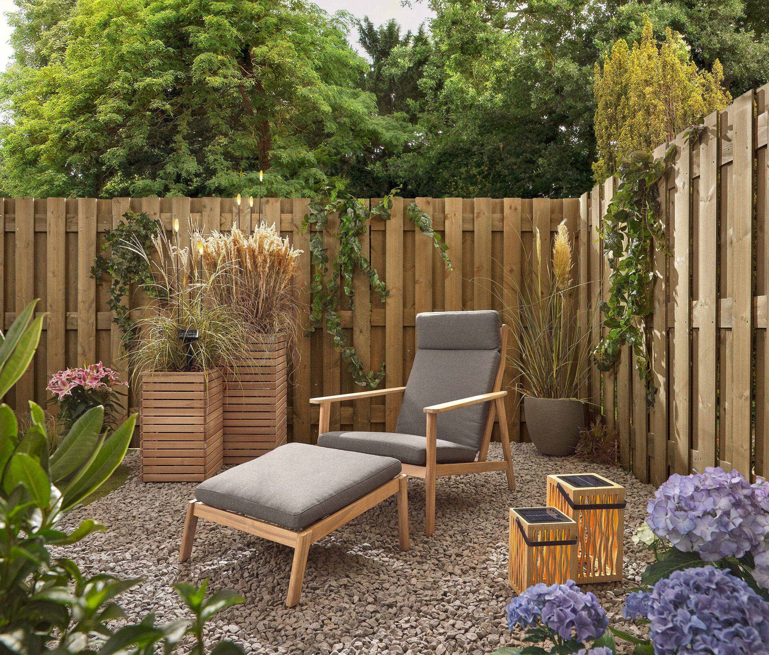 Záhrada so sivým kreslom a stoličkou, dvoma bambusovými solárnymi lampášmi a 5 LED solárnymi bodcami.