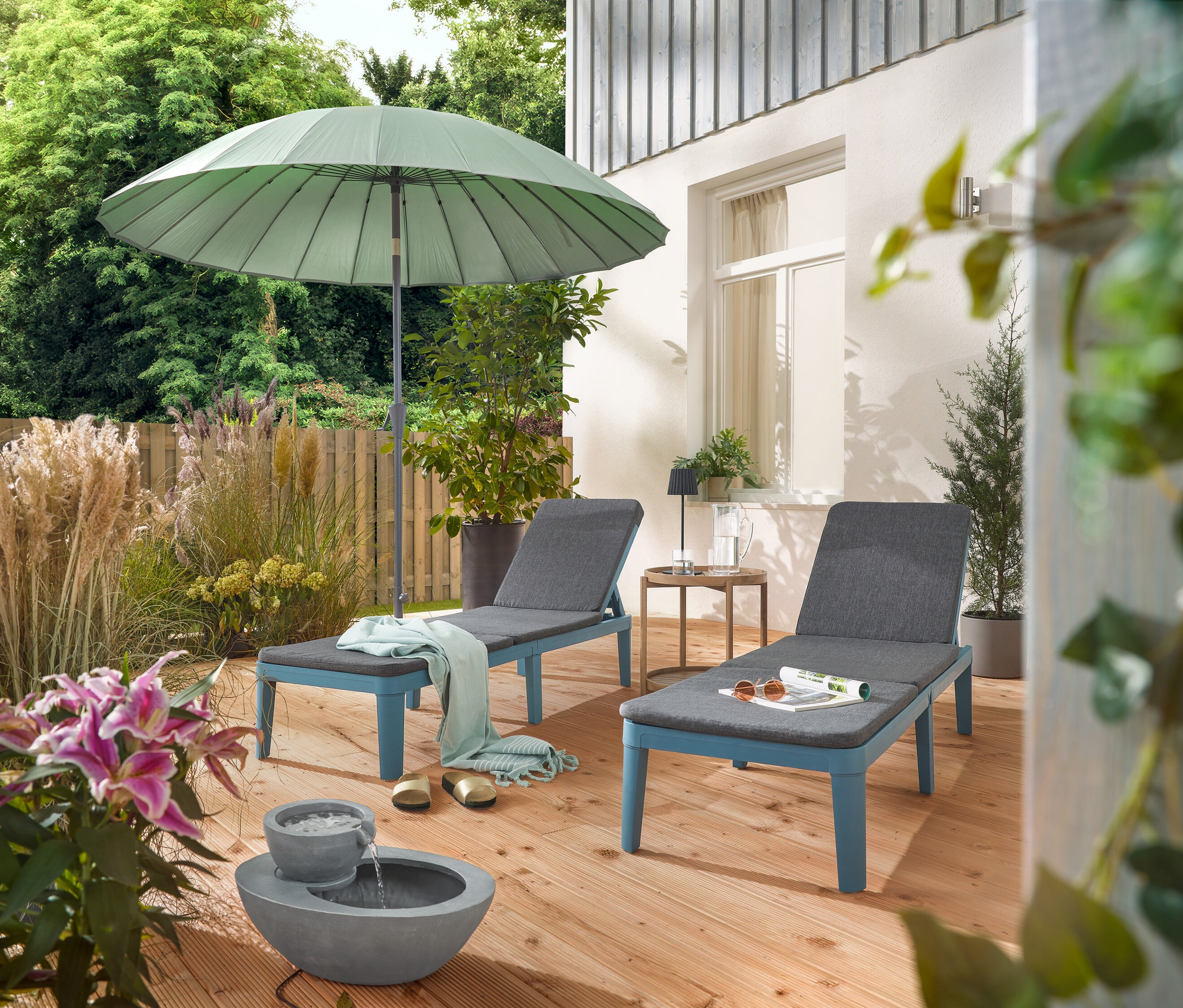 Na terase sú dve ležadlá pod svetlosivým slnečníkom Leco Shanghai a vedľa solárnej záhradnej fontány.