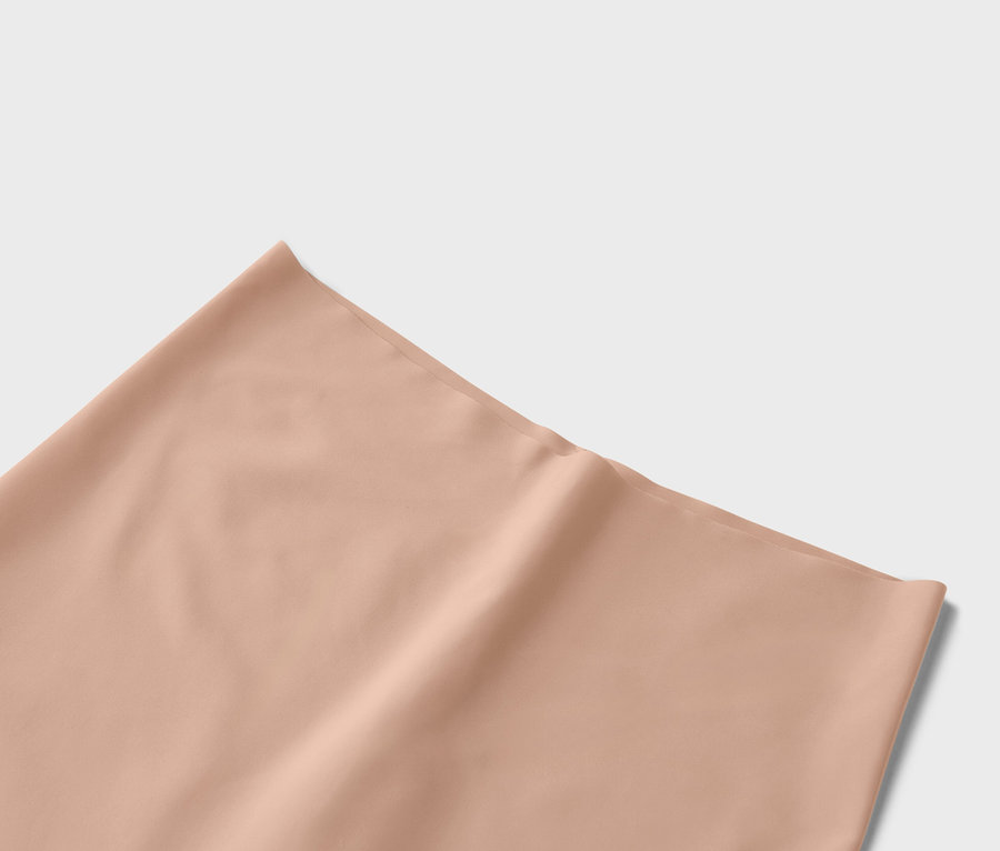 Detailná fotografia jednofarebnej látky v broskyňovej farbe.