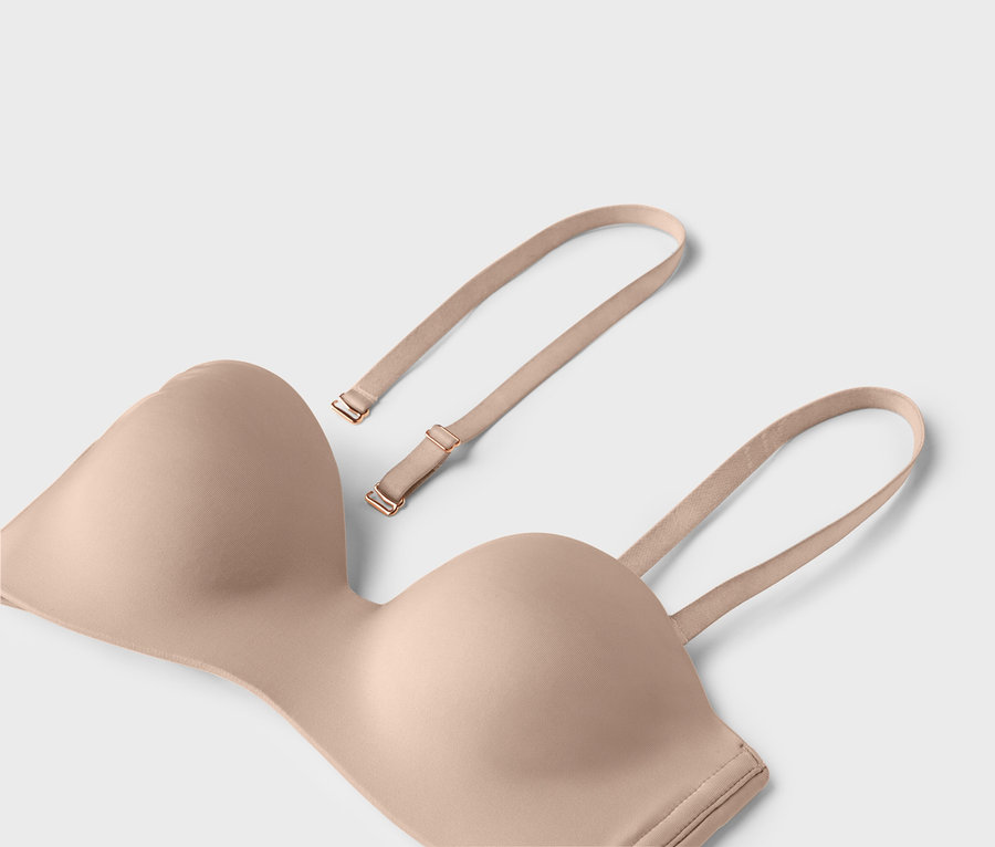 Telový bezšvový podprsenka s odnímateľnými ramienkami leží na svetlom pozadí.