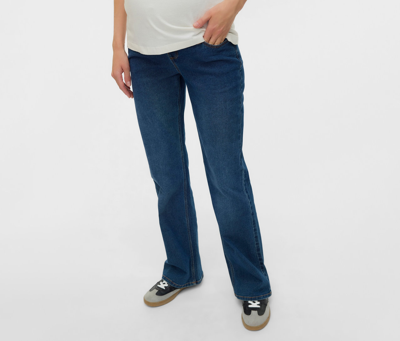 Tehotná žena v rozšírených džínsoch MAMALICIOUS »MLEDINA« a bielom tričku, ruka vo vrecku.