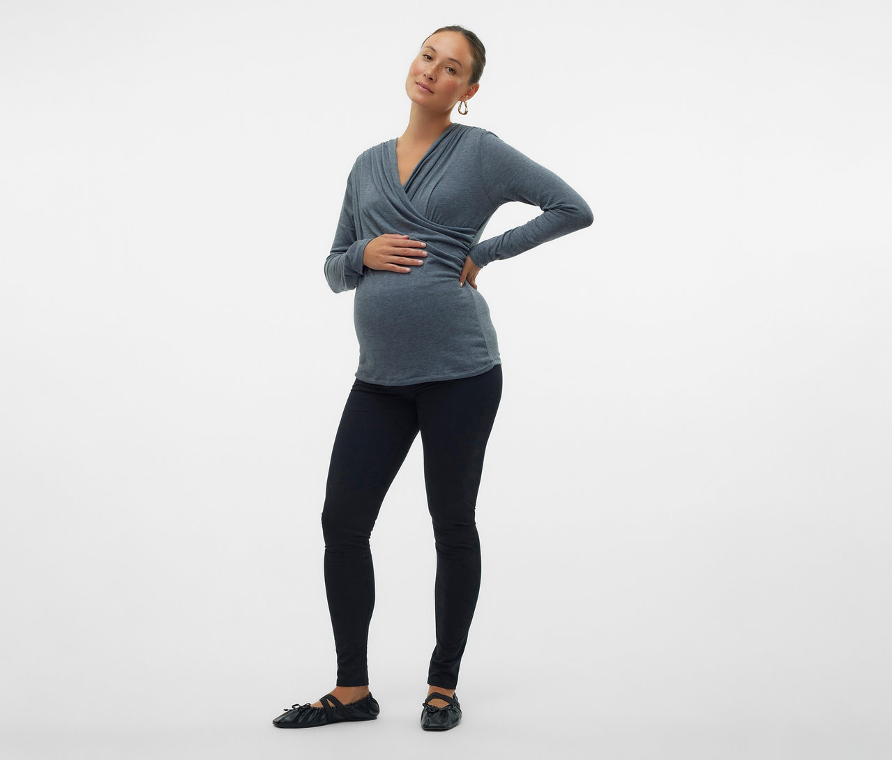 Tehotná žena nosí legínsy MAMALICIOUS v 2-balení »MLEMMA« a sivý top s dlhým rukávom. Jednu ruku drží na bruchu a druhú na boku.