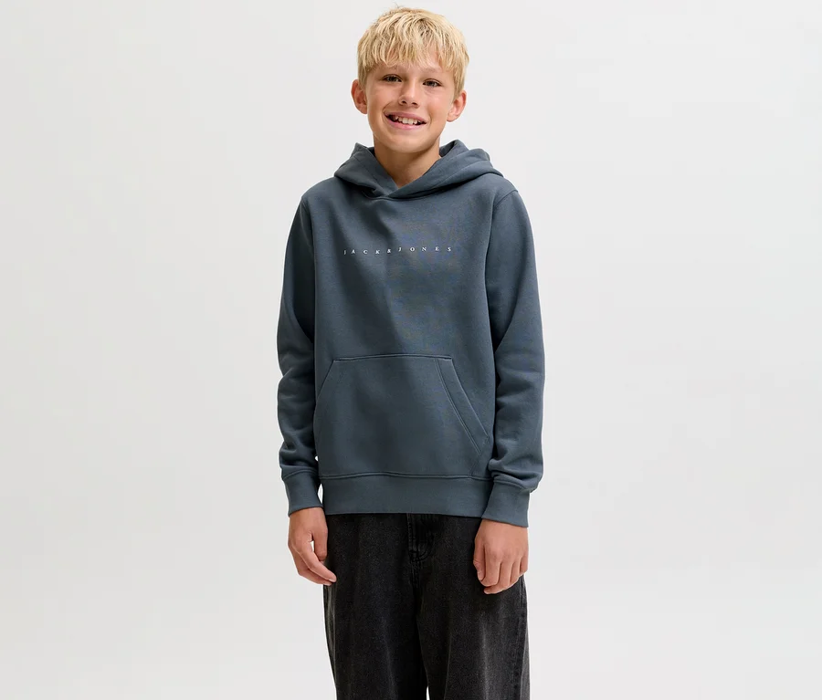 Usmiaty chlapec v tmavosivej mikine s kapucňou Jack&Jones Star s klokaním vreckom a tmavými nohavicami.